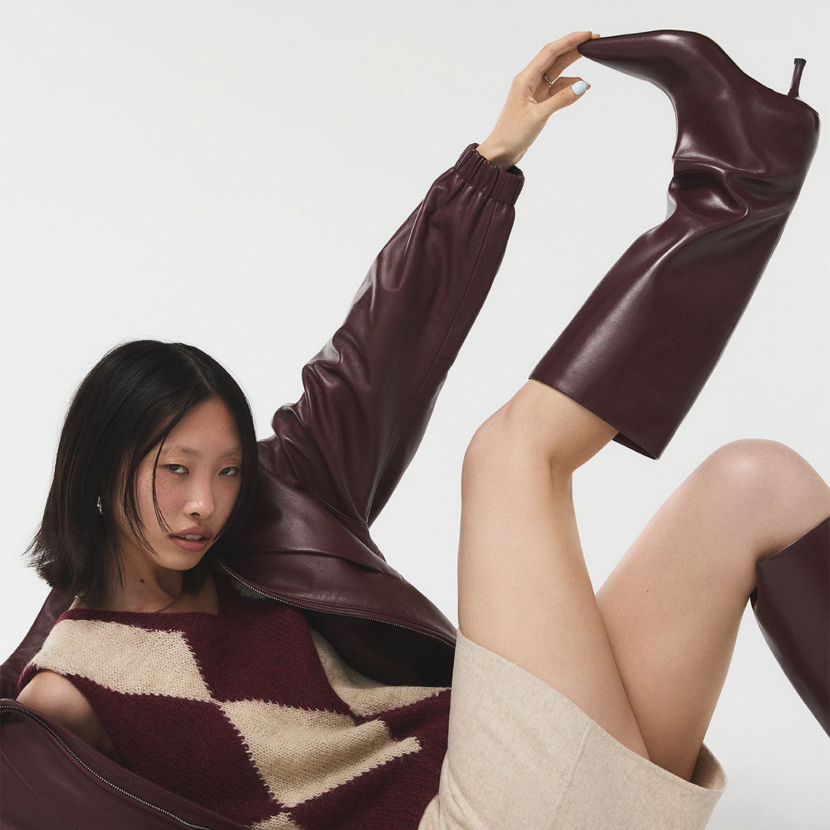 Woman wearing a burgundy outfit with matching boots on a white background