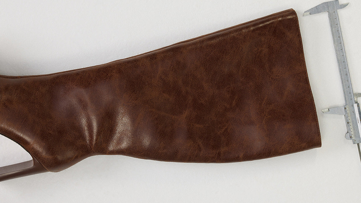 Brown leather boot on a white background with a caliper for scale.