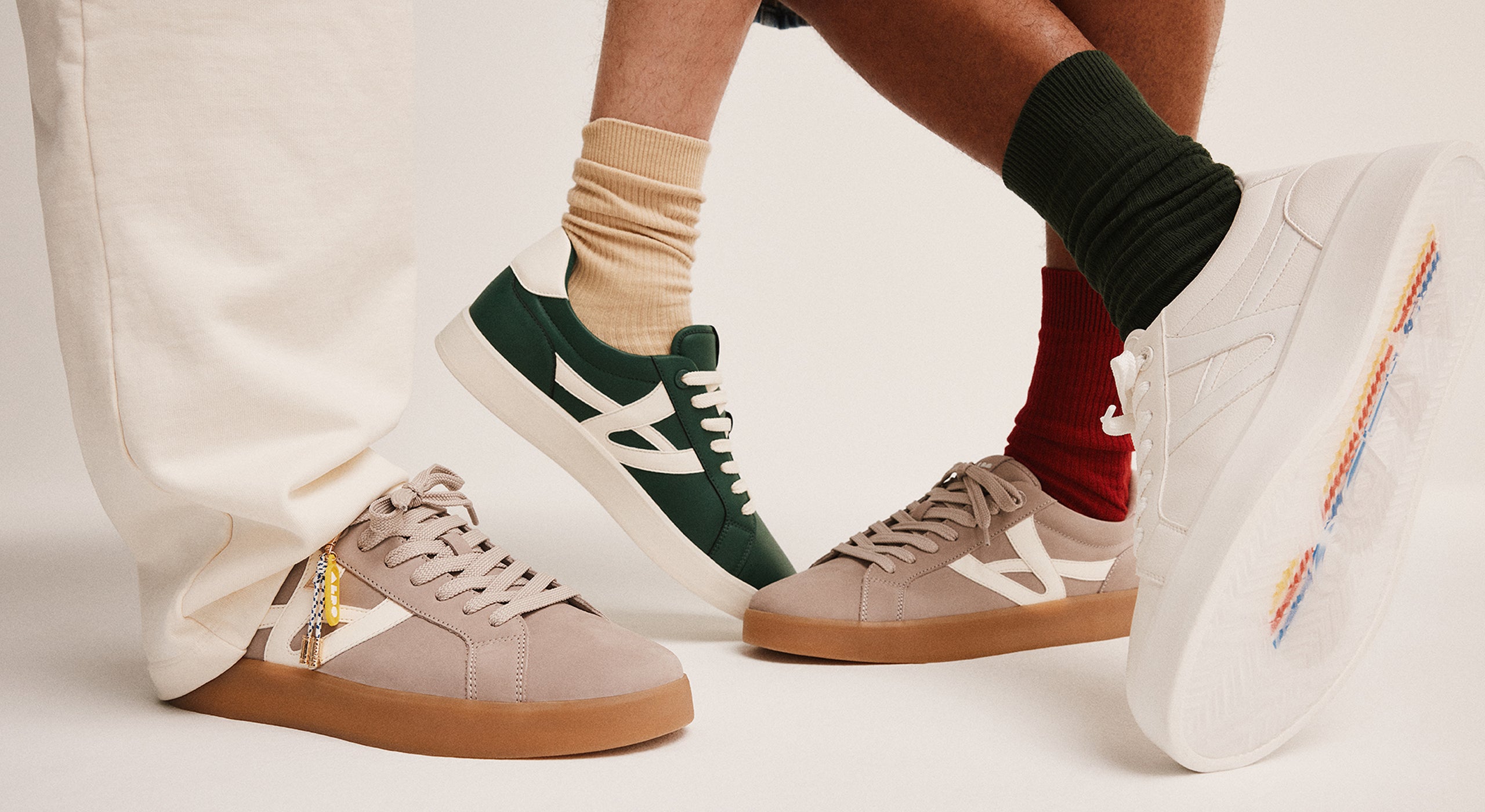 Four pairs of sneakers worn by different people on a white background