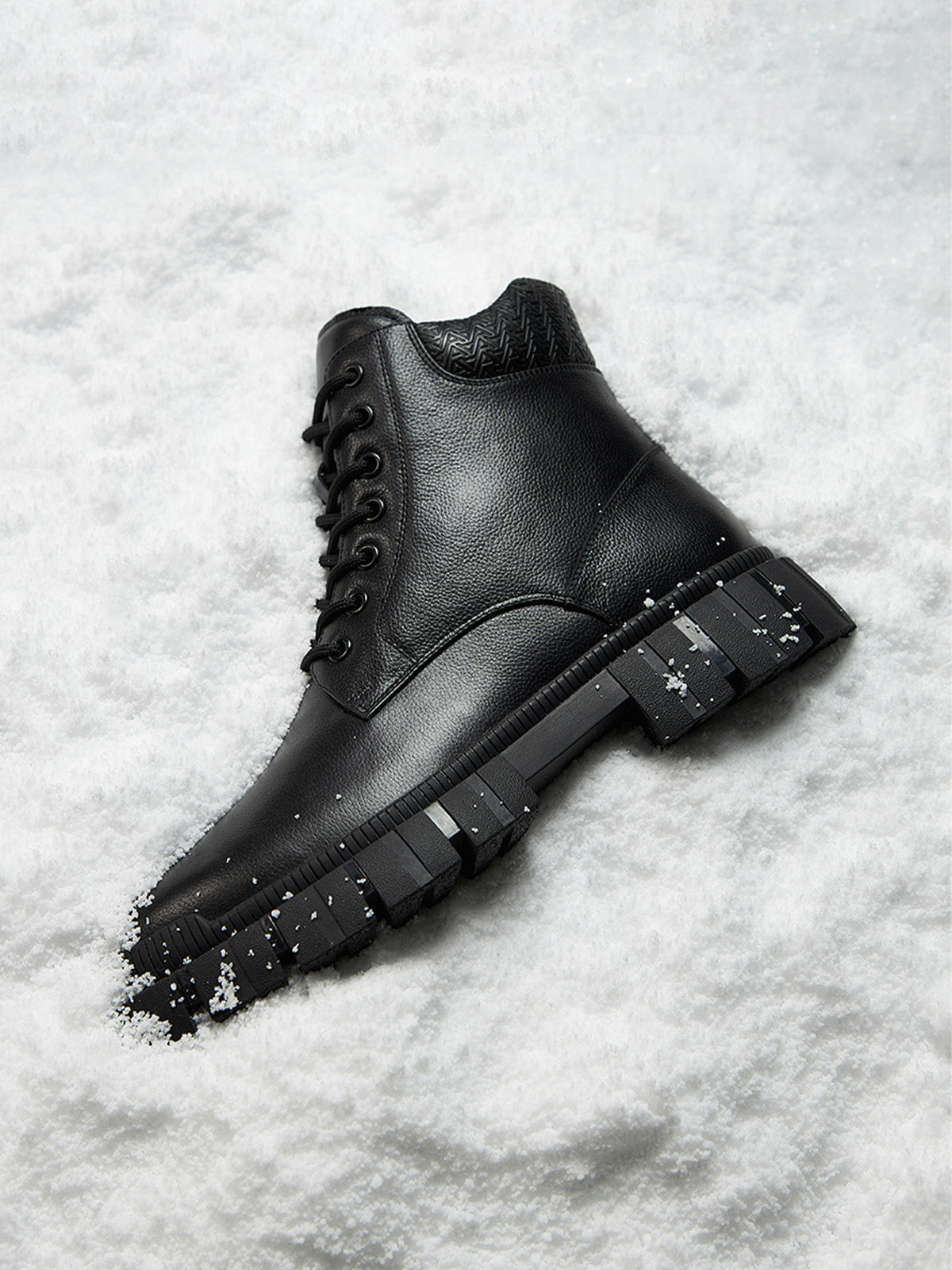 Black leather boot with chunky sole on a snowy background