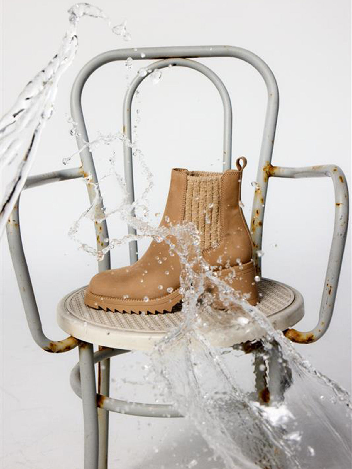 Tan ankle boot being splashed with water