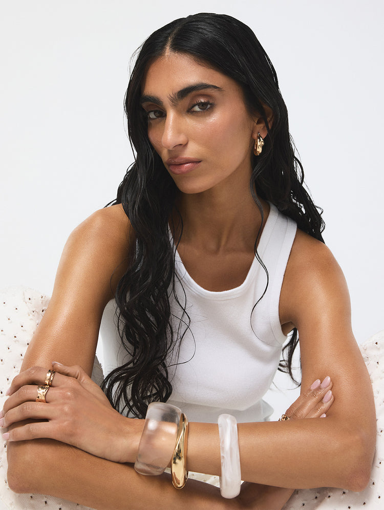Woman wearing bangle bracelet stack jewelry against a white background