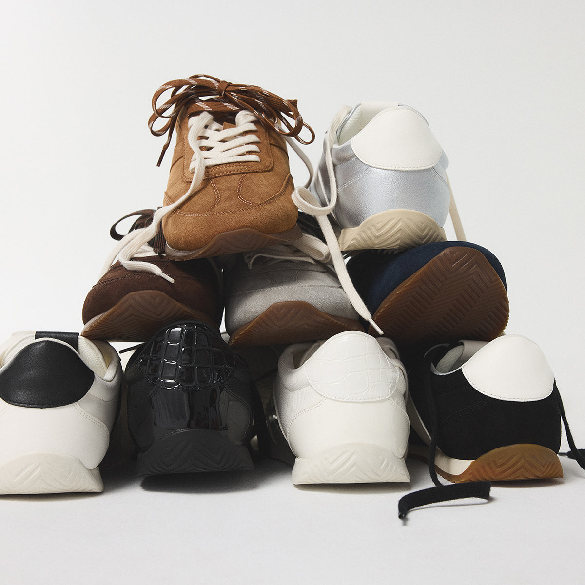 Pile de sneakers divers sur fond blanc