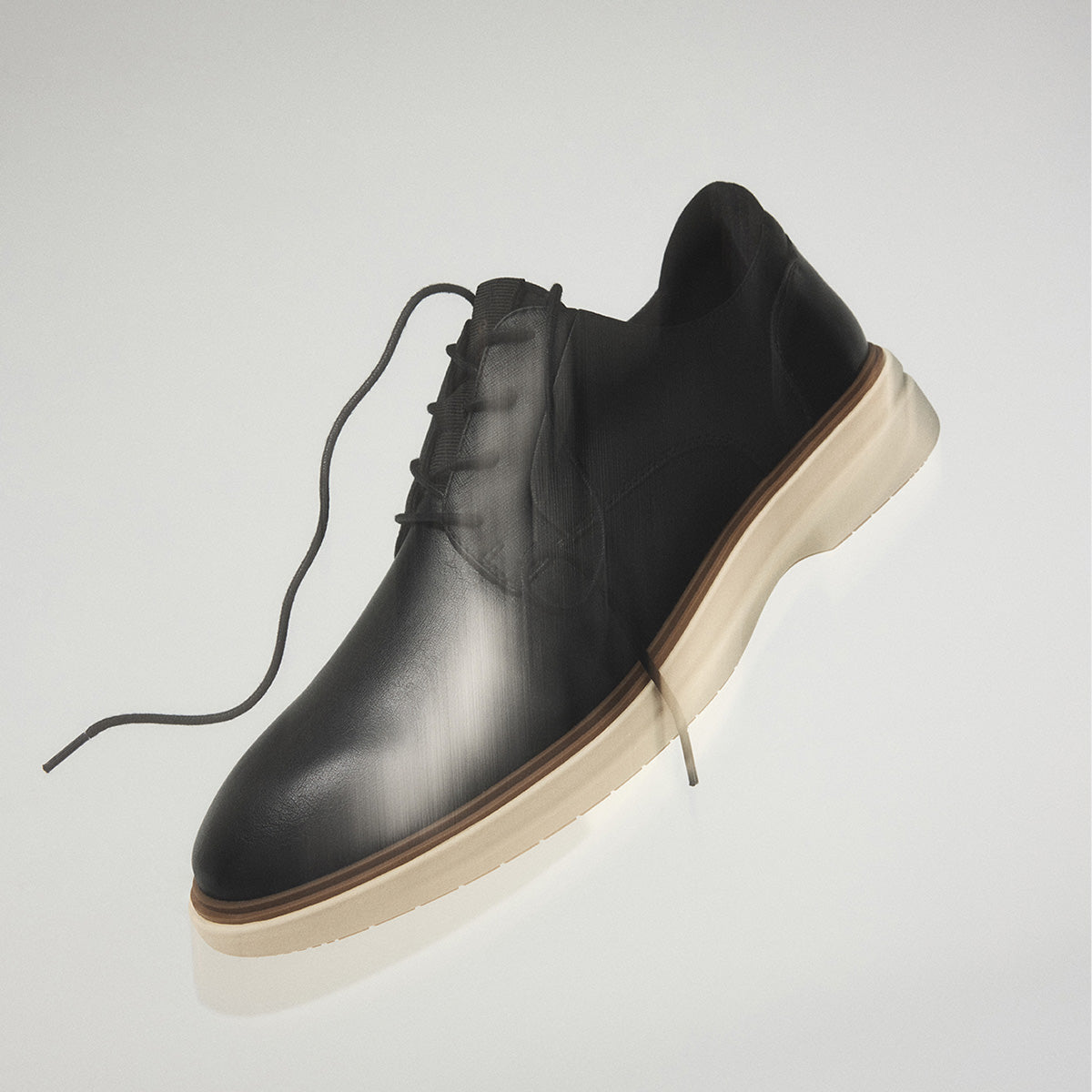 A black leather lace-up shoe with a thick beige sole, shown floating against a light gray background.