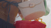 woman at the beach with textured handbag and sandals with colorful buckets on the sand.