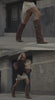 A woman strolls down the street in a brown suede jacket layered over a cream silk lace dress, styled with brown boots and a matching brown suede shoulder bag. Carrying a paper bag filled with groceries, she embodies effortless, everyday elegance.