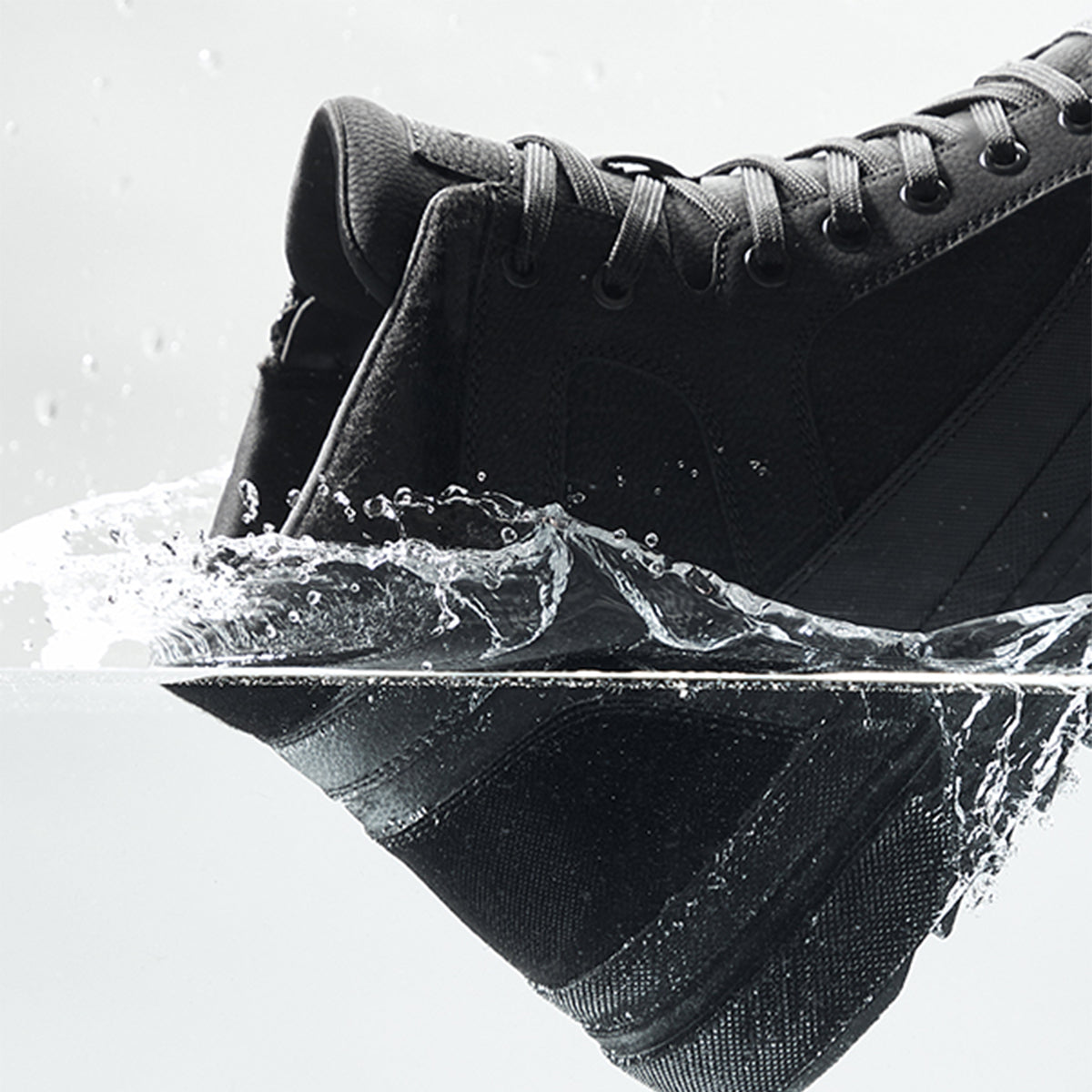 Black sneaker with water droplets on a white background