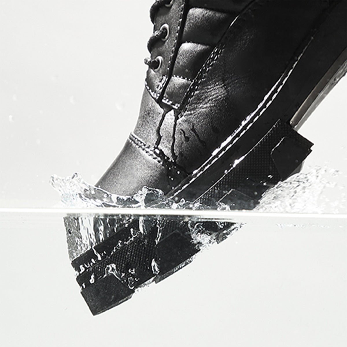Black leather boot splashing in water on a white background