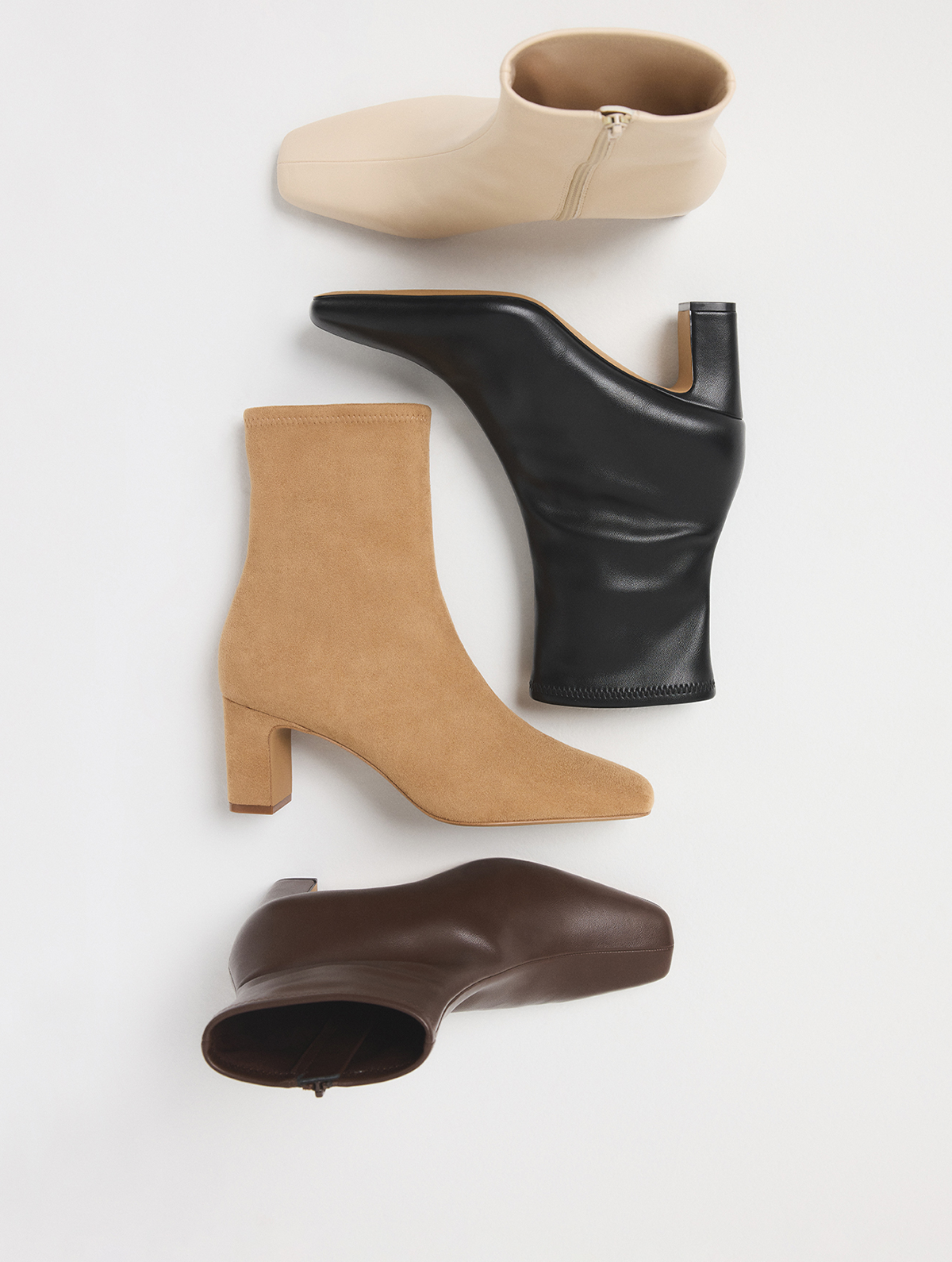 Quatre bottillons pour femme de couleurs et de styles variés, disposés verticalement sur un fond blanc épuré. Les modèles comprennent une bottine beige à fermeture éclair, une bottine noire en cuir à talon bloc, une bottine en suède tan à talon bloc et une bottine en cuir brun foncé.