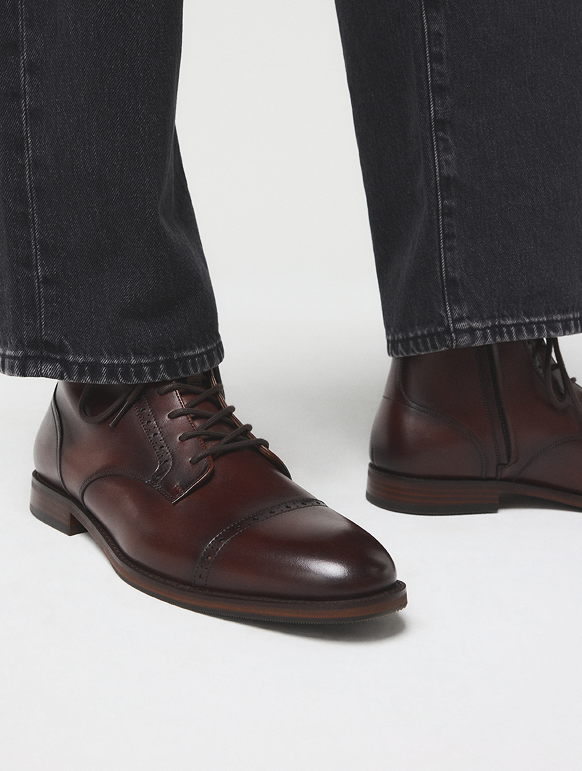 Une vue rapprochée des pieds d’une personne portant des souliers richelieu en cuir brun foncé avec un jean noir, photographiés sur un fond de studio gris pâle.

Provide your feedback on BizChat