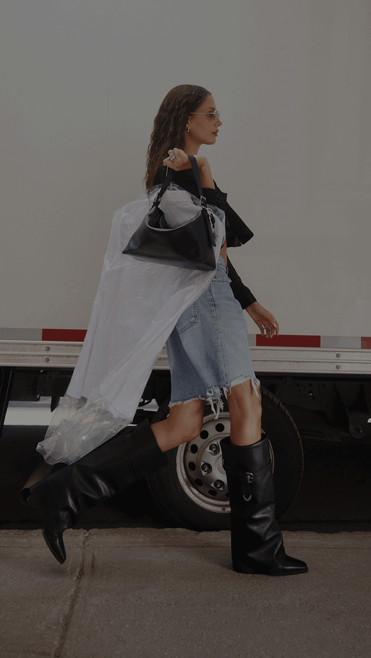 A gif showing a woman walking beside a truck while wearing black knee-high boots and a sheer white duster. And a close-up of the boots on a person's feet with dark jeans and a truck tire in the background.