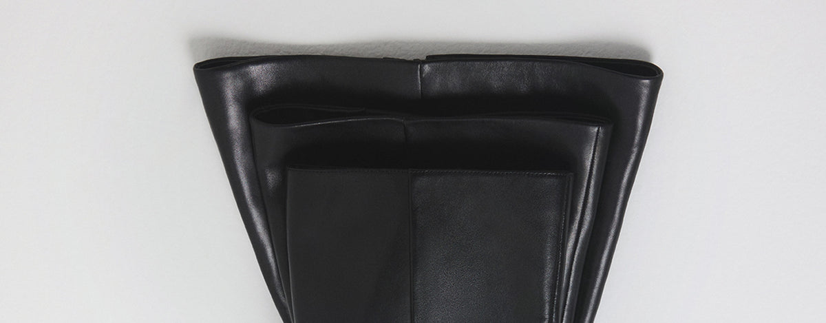 Three top of black leather boot with a triangular slouch, photographed from directly above on a light gray background.